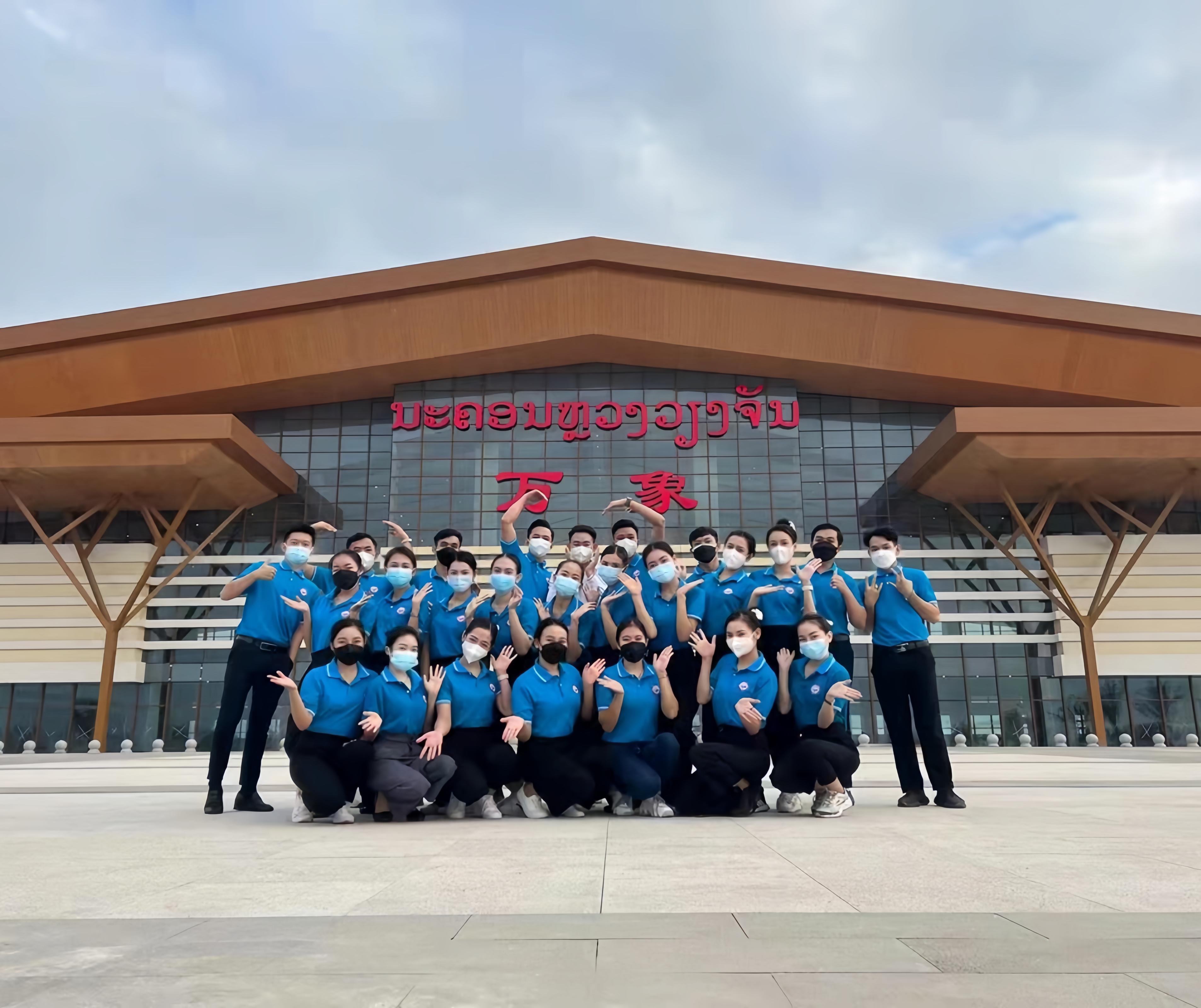 學(xué)生上崗前在老撾萬(wàn)象高鐵站前合影（其中5人為貴陽(yáng)職業(yè)技術(shù)學(xué)院培訓(xùn)班學(xué)生）。 貴陽(yáng)職業(yè)技術(shù)學(xué)院供圖